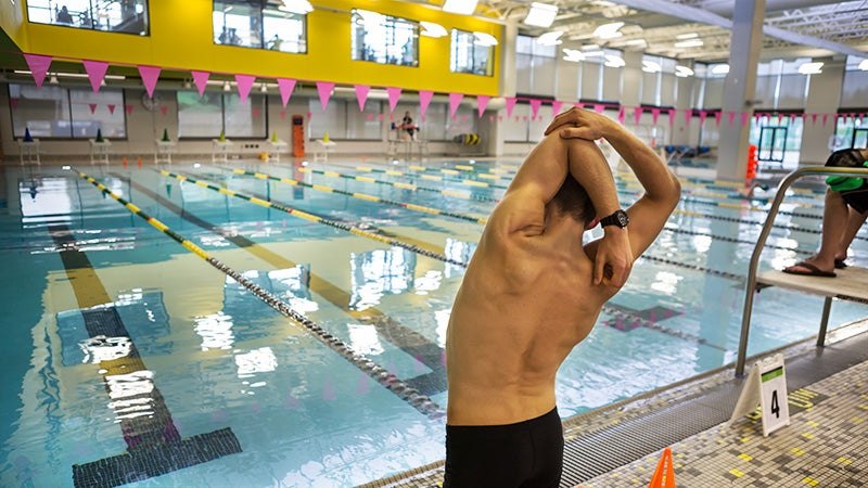 A swimmer stretching before entering the pool