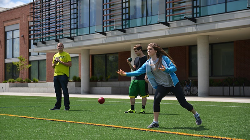 Students playing bocce ball on turf fields in front of Student Recreation Center.