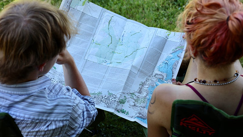 Two people sit in camp chairs and look at a hiking map