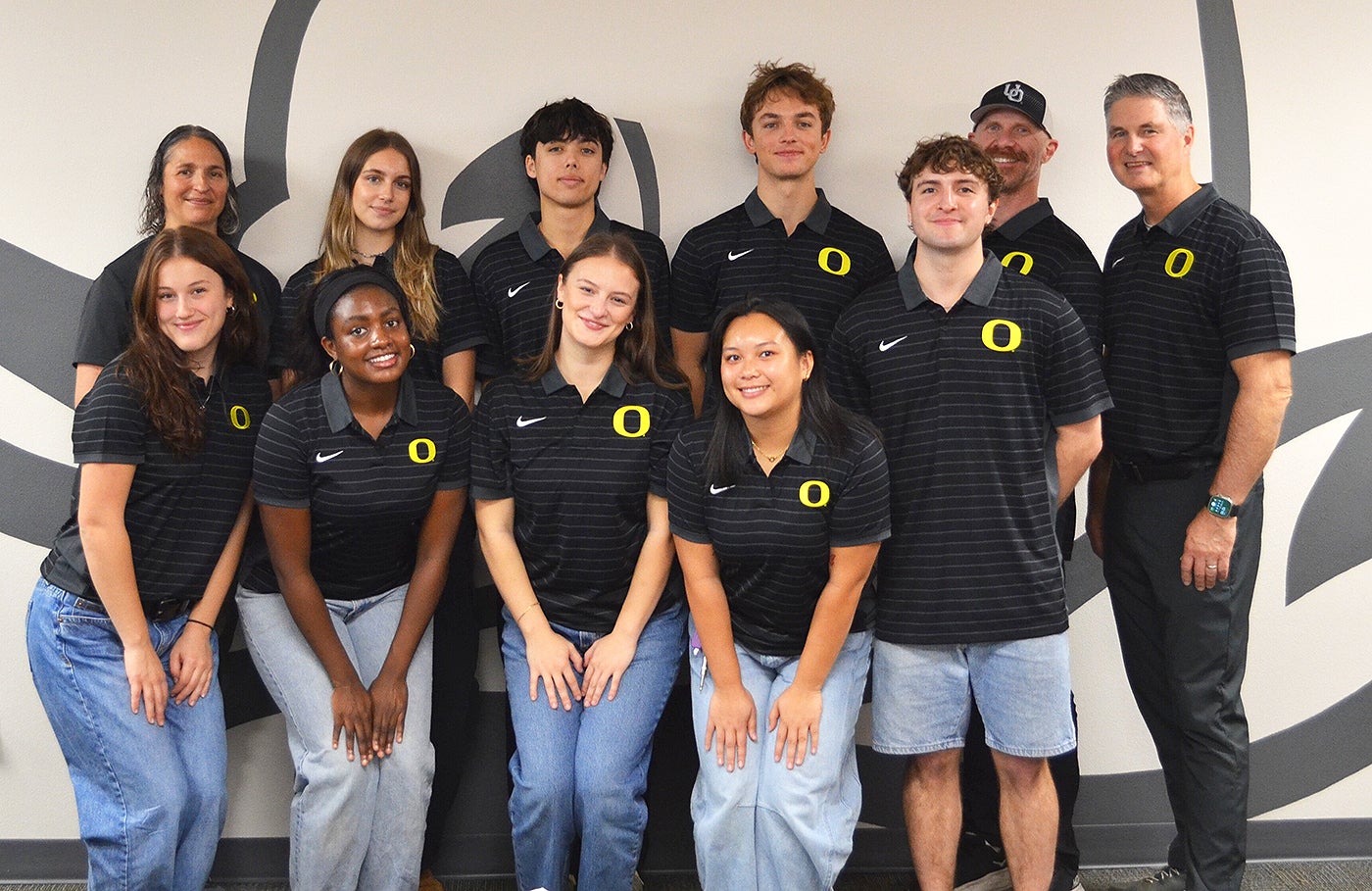Eleven students and staff in black polo shirts