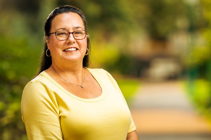 woman with long black hair wearing a yellow blouse