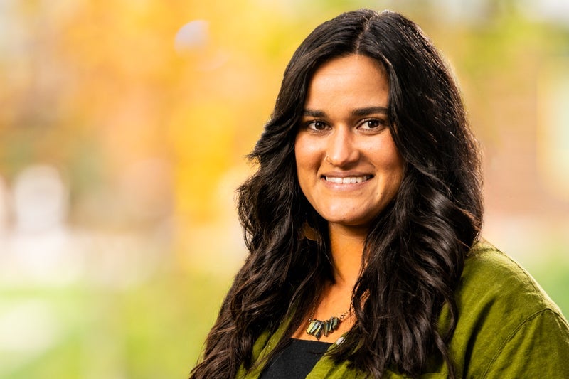woman with long black hair wearing an olive green sweater