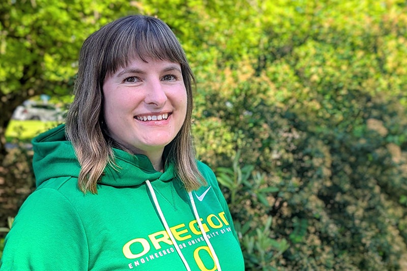 Woman with shoulder-length brown hair wearing a green Oregon sweatshirt