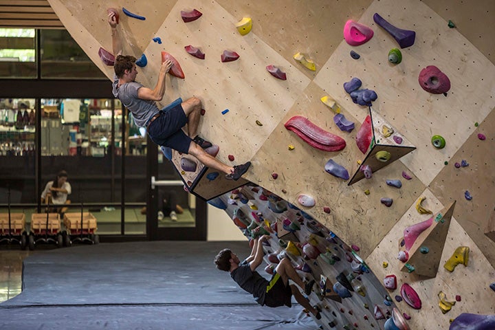 Two people work their way up the bouldering wall.