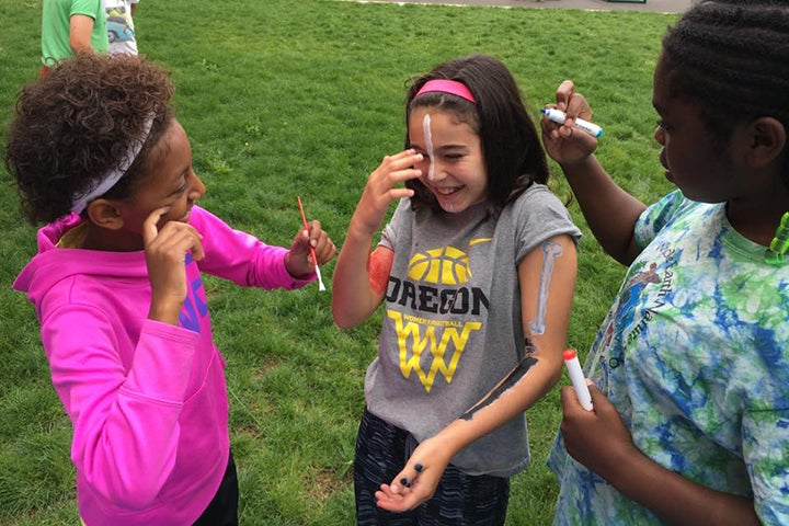 Female-identified campers play with face paint