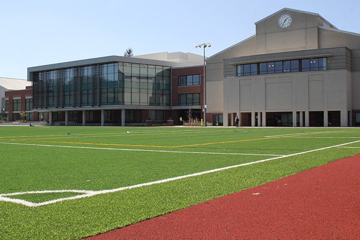Wide view of empty turf field with the Rec Center in the background.